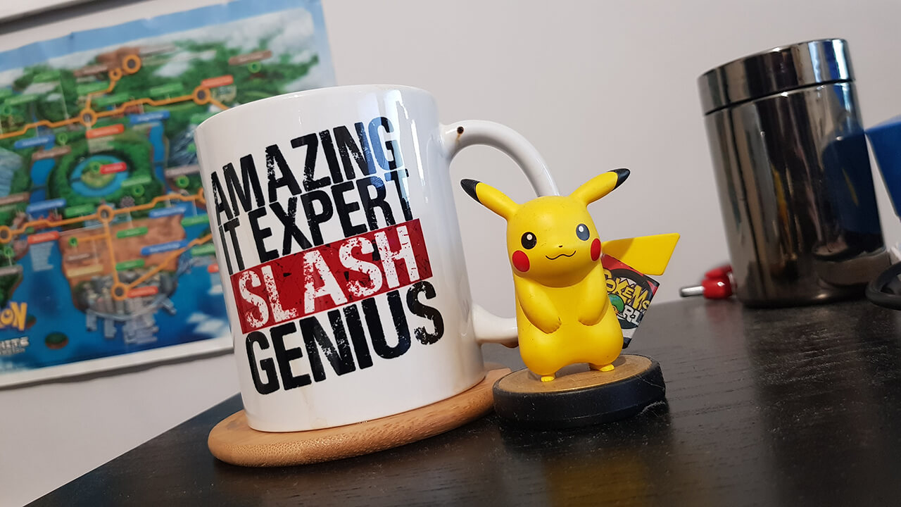 Drinks mug reads 'amazing IT expert slash genius' next to small Pikachu figurine