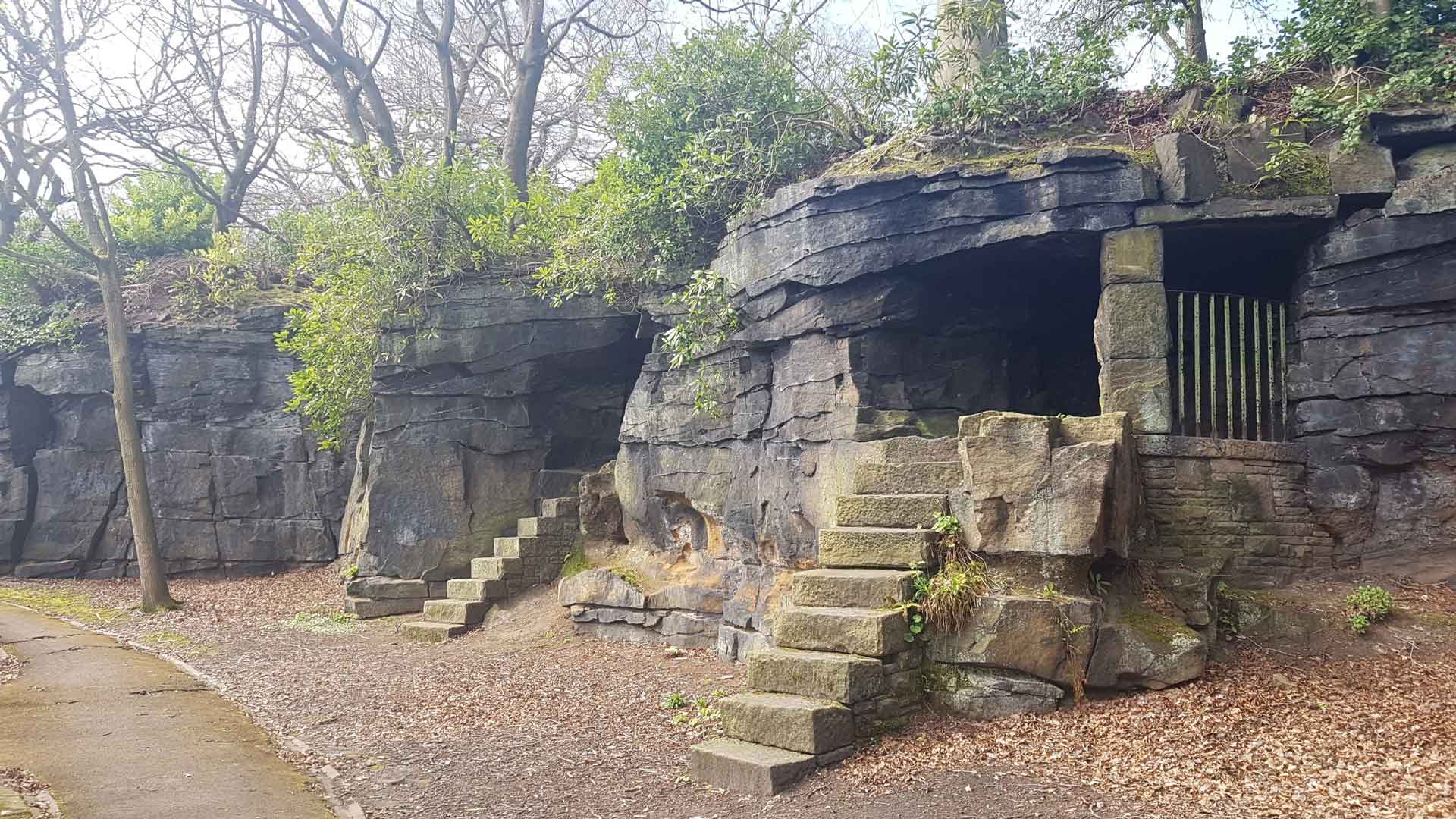 A photograph of some rock huts in a yorkshire woodland
