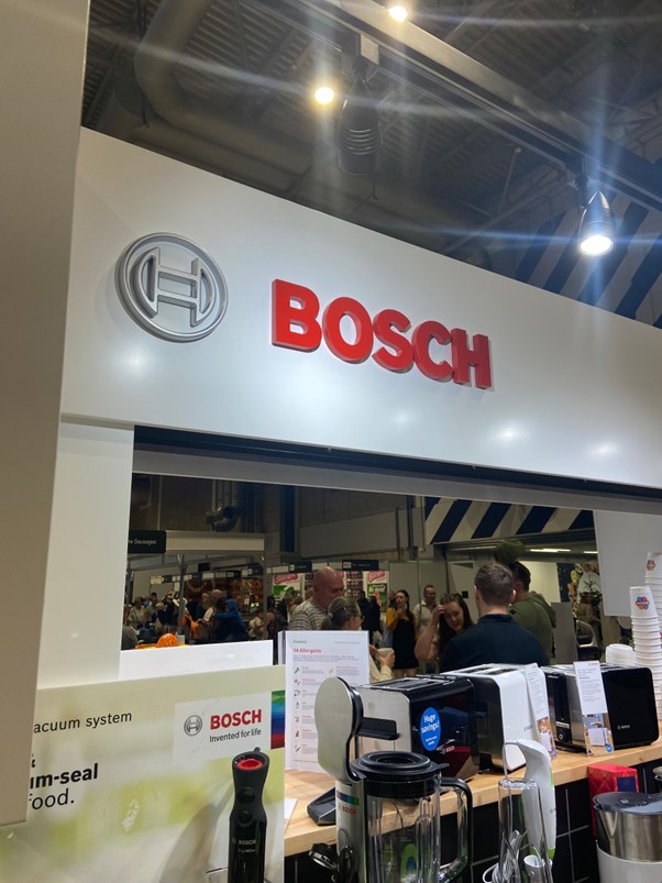 A crowd of visitors can be seen through a Bosch exhibition stand, displaying small kitchen appliances