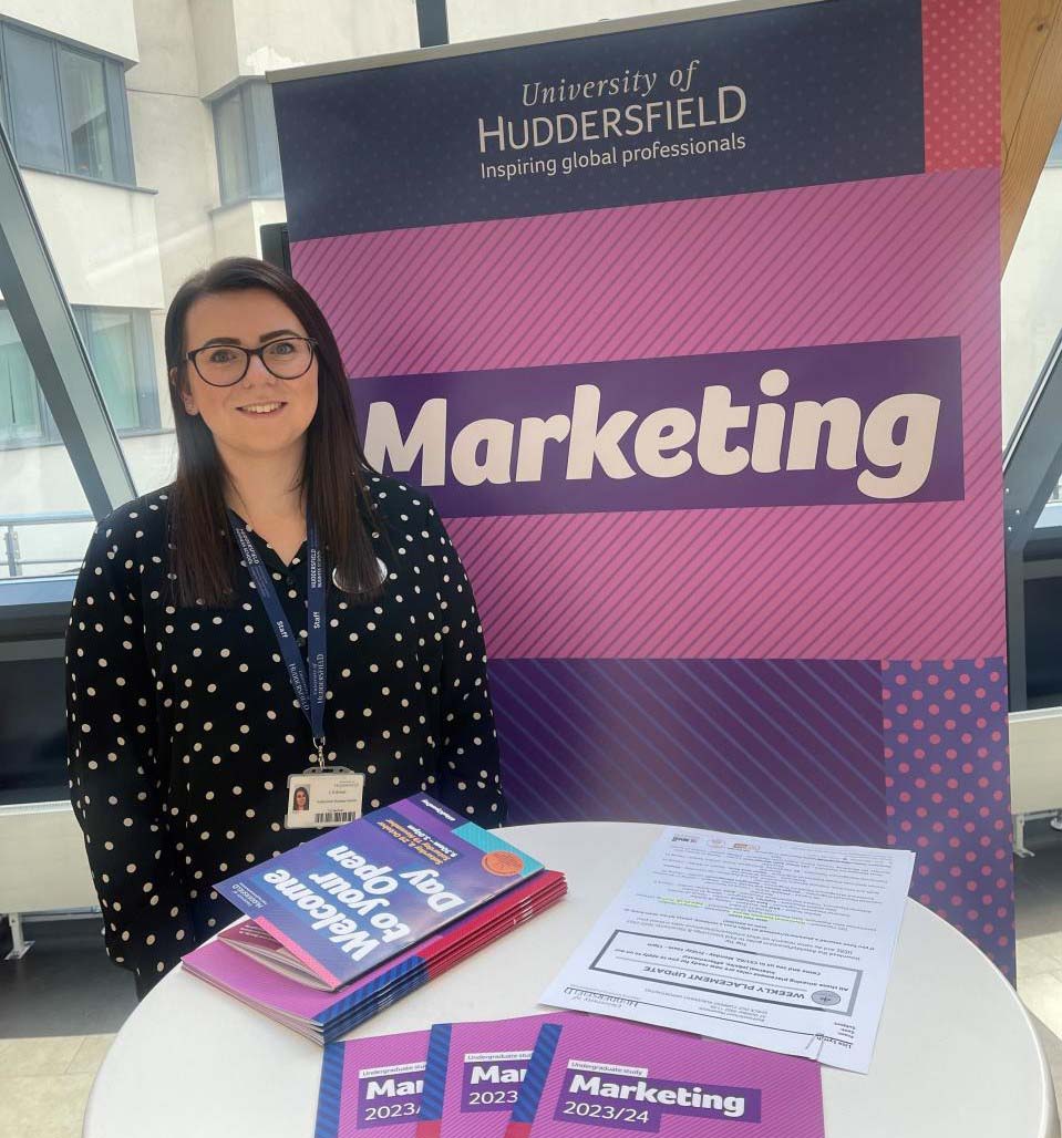 Loren Birkett stood in front of a marketing banner at an Open Day