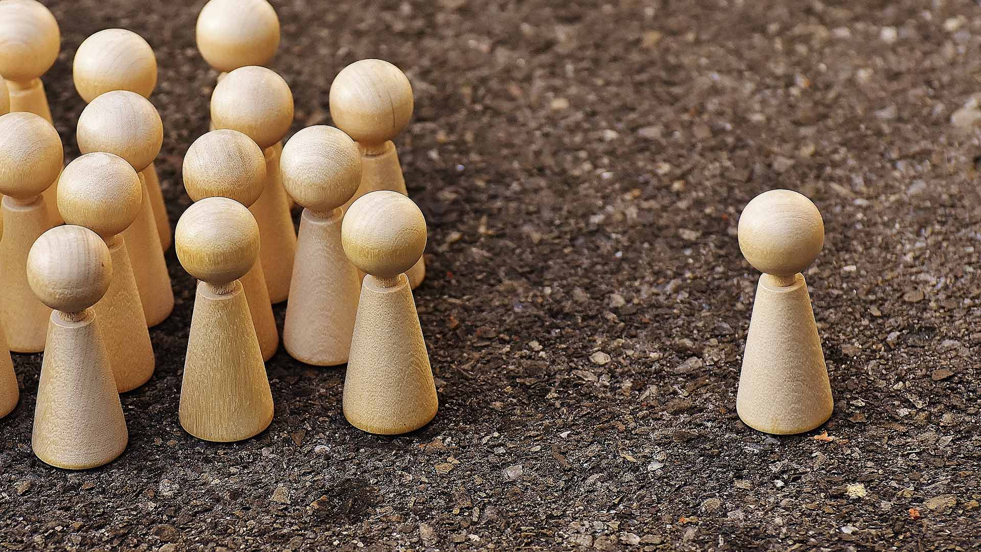 One wooden figure stood away from a group