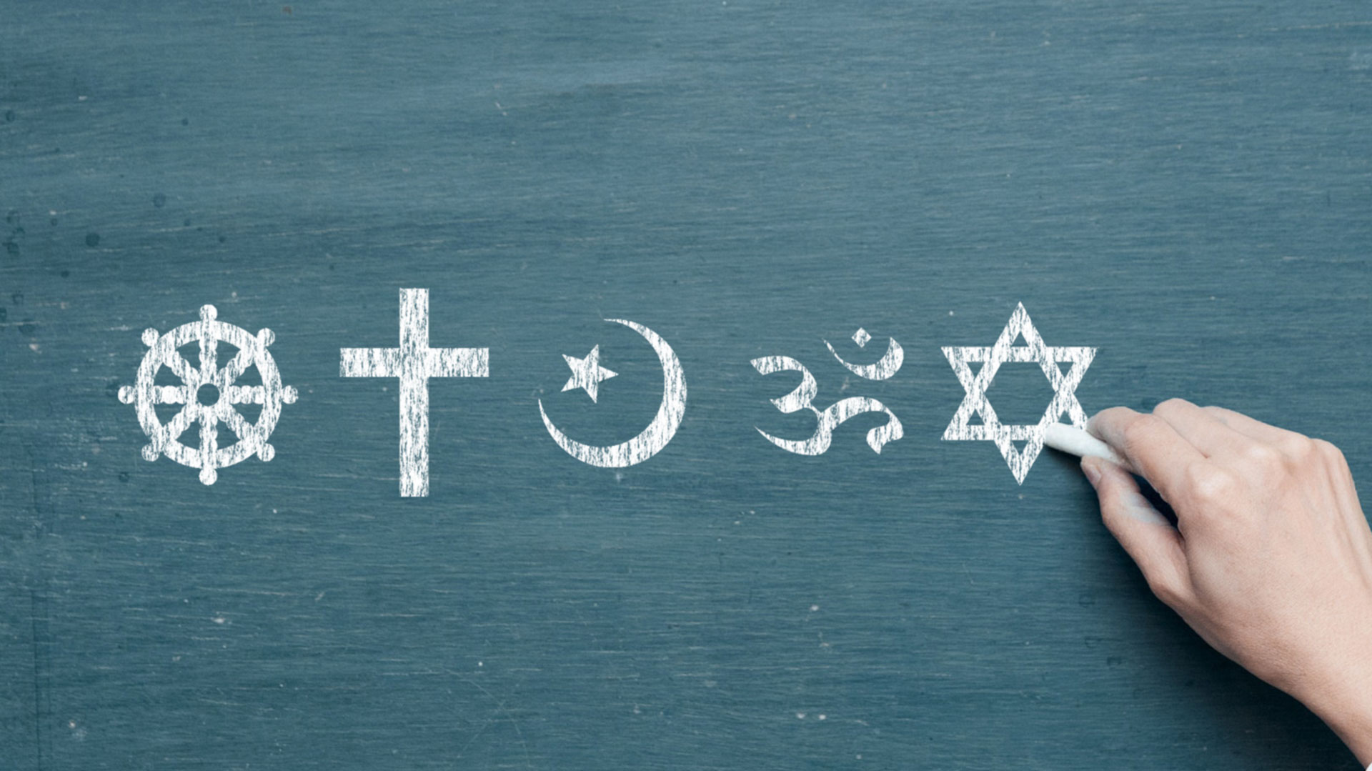 Hand drawing religious symbols on blackboard