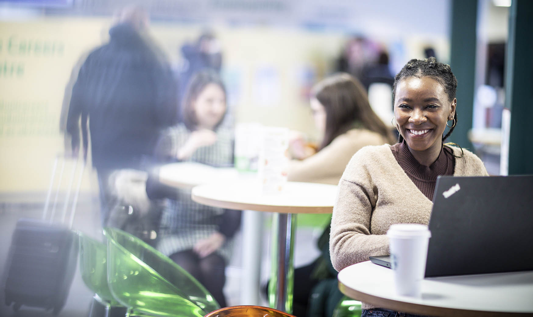 A student sat smiling while using their laptop