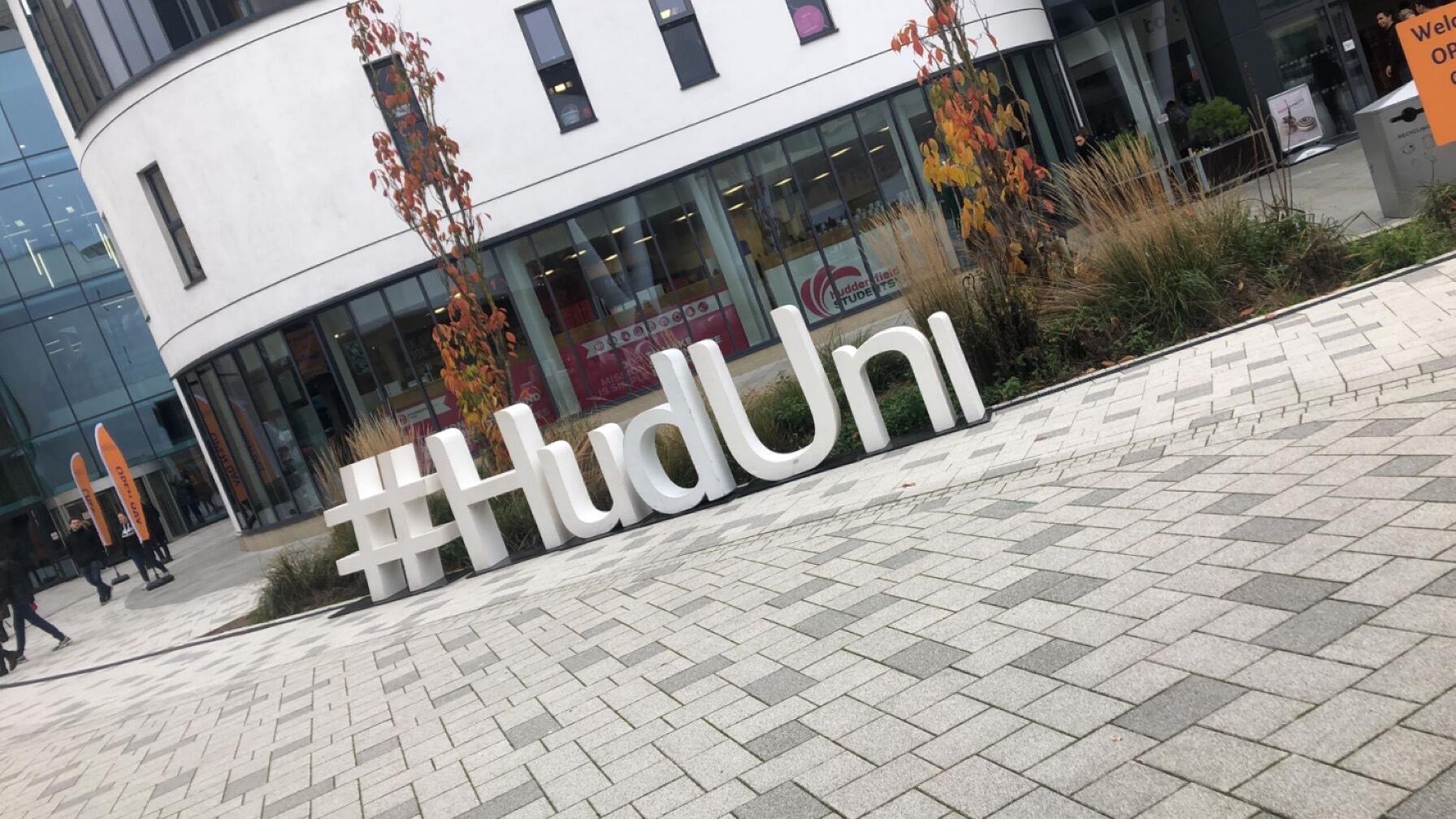 Giant white letters spelling out #HudUni stand outside the Student Central building on the main campus plaza