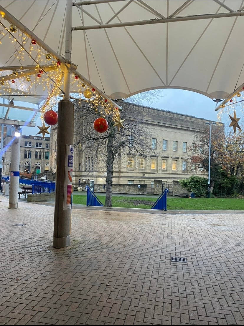 Piazza centre in Huddersfield, a small grass convergence with Huddersfield library in the background