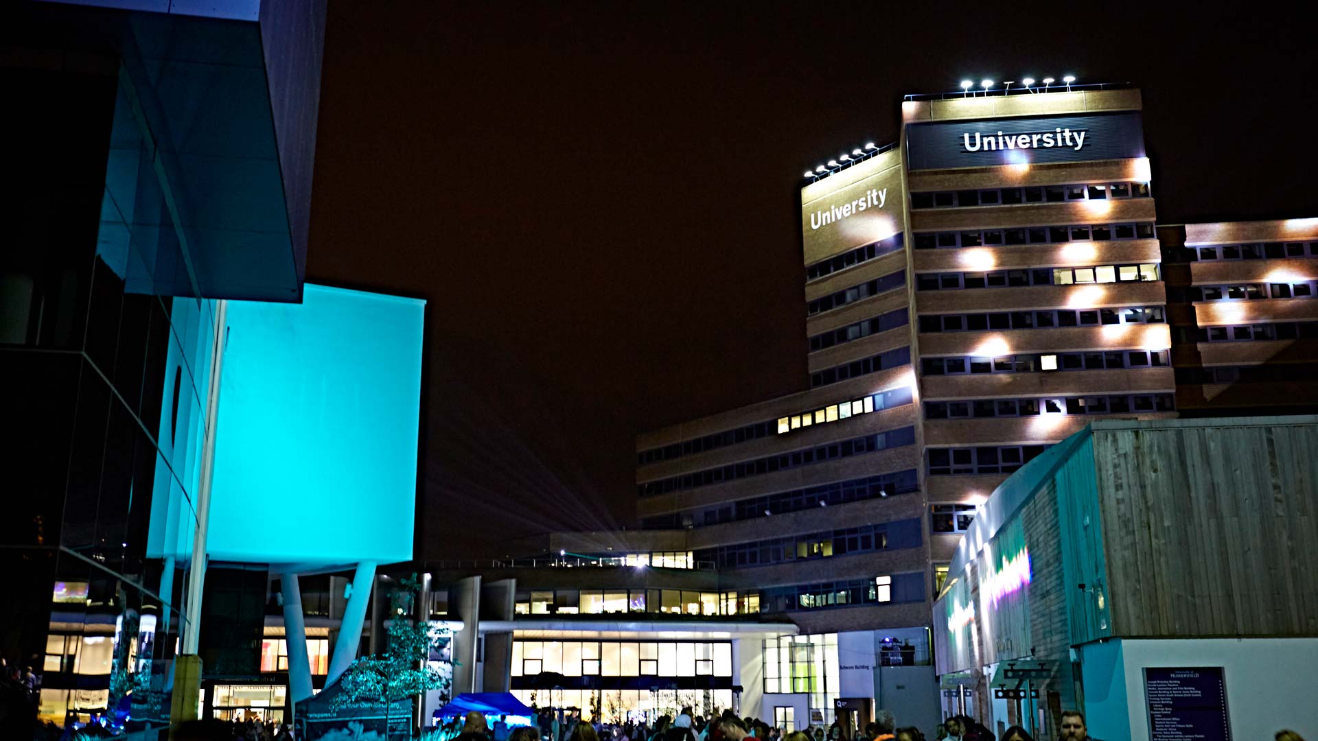 Crowd in the main campus of the University of Huddersfield at night time.
