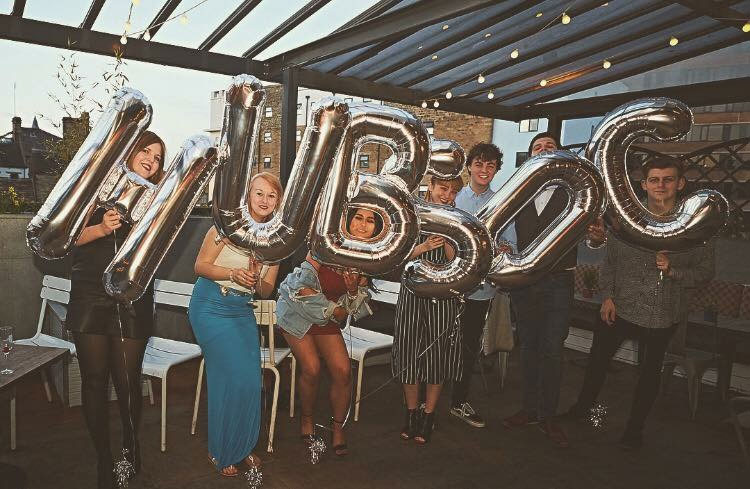 A picture of seven students holding helium balloons spelling HUBSOC