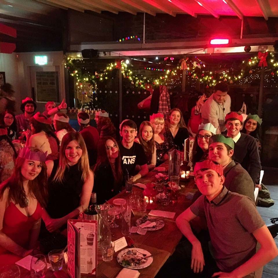 A picture of a group of students sitting around a long table having a meal. 