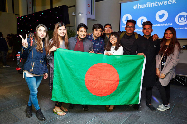 A group of students in a global society smiling and holding a flag