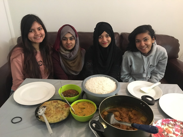 A group of students posing for a photo with a assortment of food in front of them