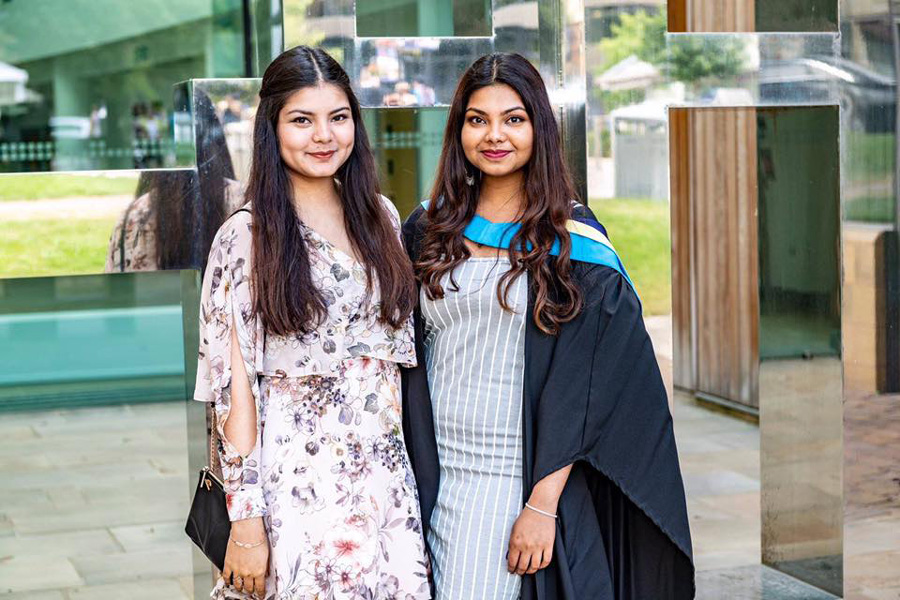 A picture of a graduate and a student posing together.