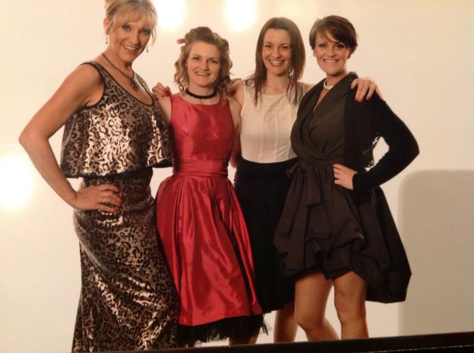 Nikki Dawson posing with three other women in dresses.
