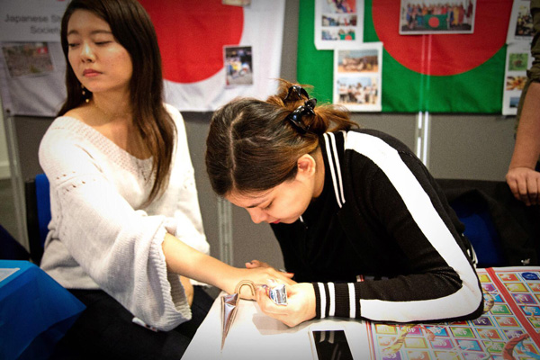 A student having a pattern painted onto her hand.