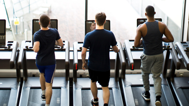 A photograph of three men using treadmills.