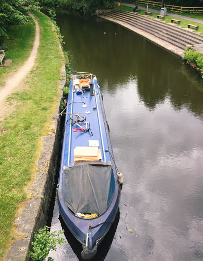 A photo of a canal boat parked in the canal next to The University of Huddersfield