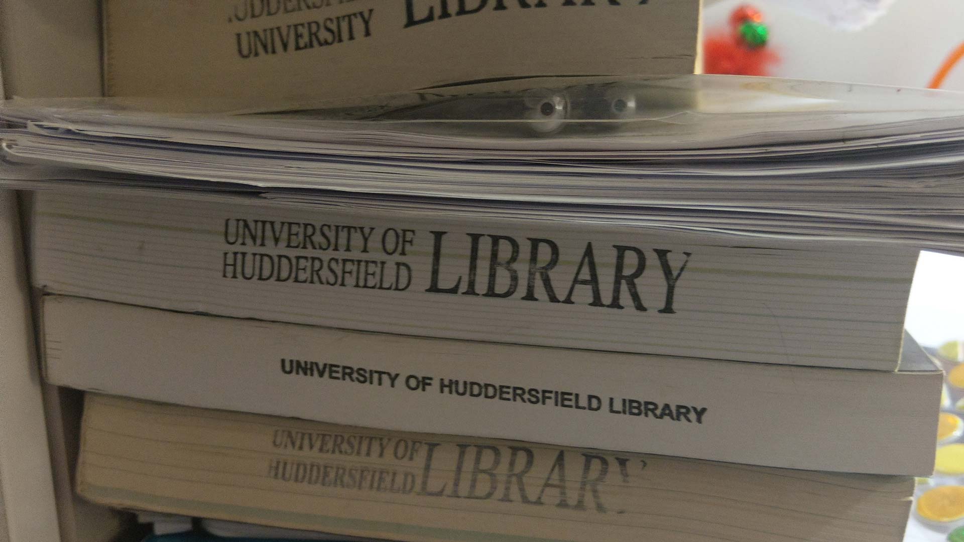 A photo of a pile of books from the University library.