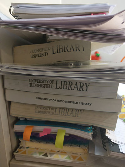 A photo of a pile of books from the University library.