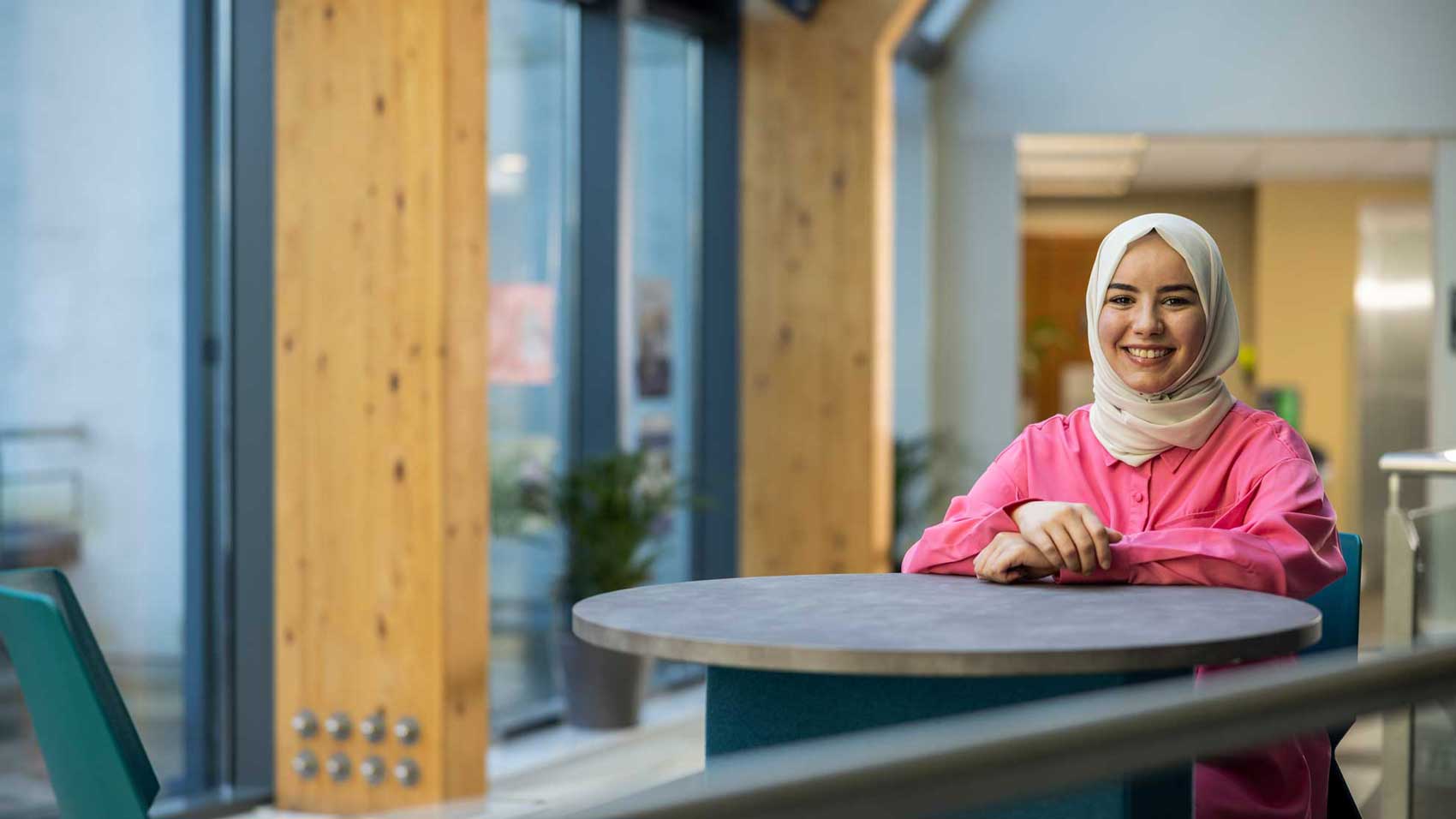 Hadil sitting a table smiling