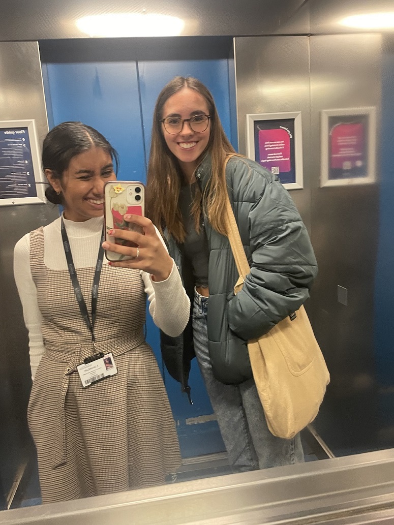 Two smiling students taking a selfie in a lift