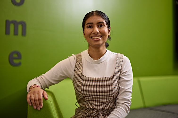 A smiling student sitting in front of a green wall