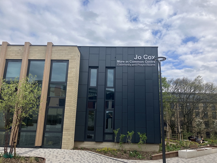 A stone and dark cladded building in front of a blue sky