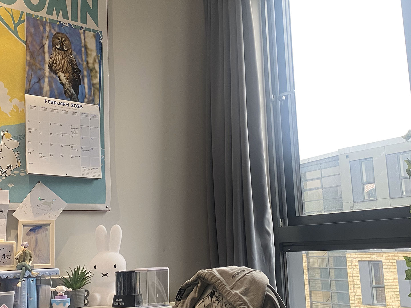 Interior view of Bruce bedroom with a wall calendar featuring an owl, a row of decorative figurines on the windowsill, and a view of Huddersfield through the window.