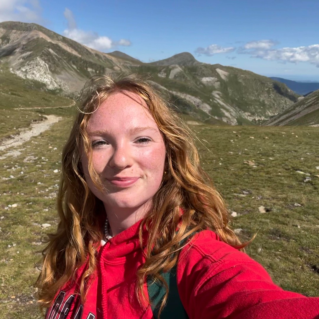 A person in a red top smiling, taking a selfie