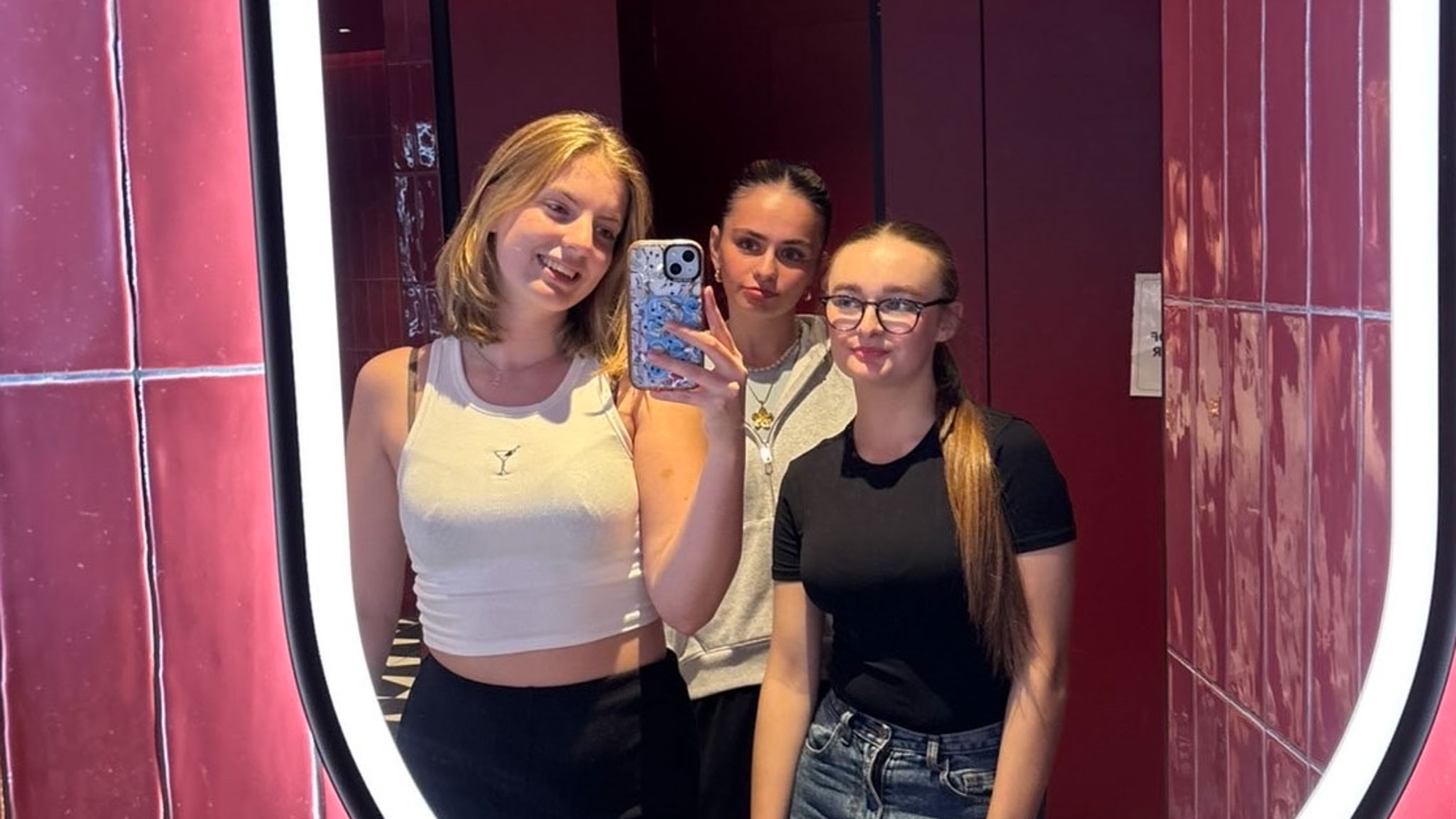 A group of three students taking a selfie in a mirror