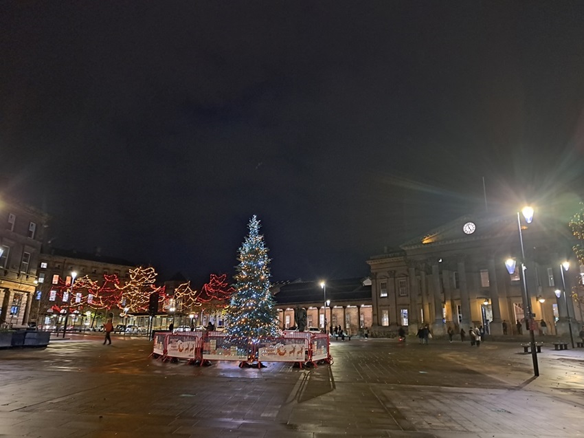 The square outside Huddersfield Railway Train Station at night with the Christmas tree lights lit