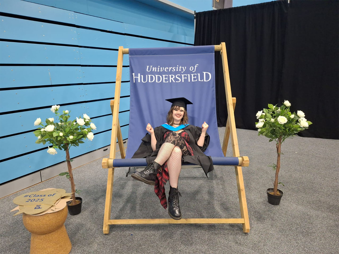 Maisy in academic regalia sits on a large deck chair labeled 