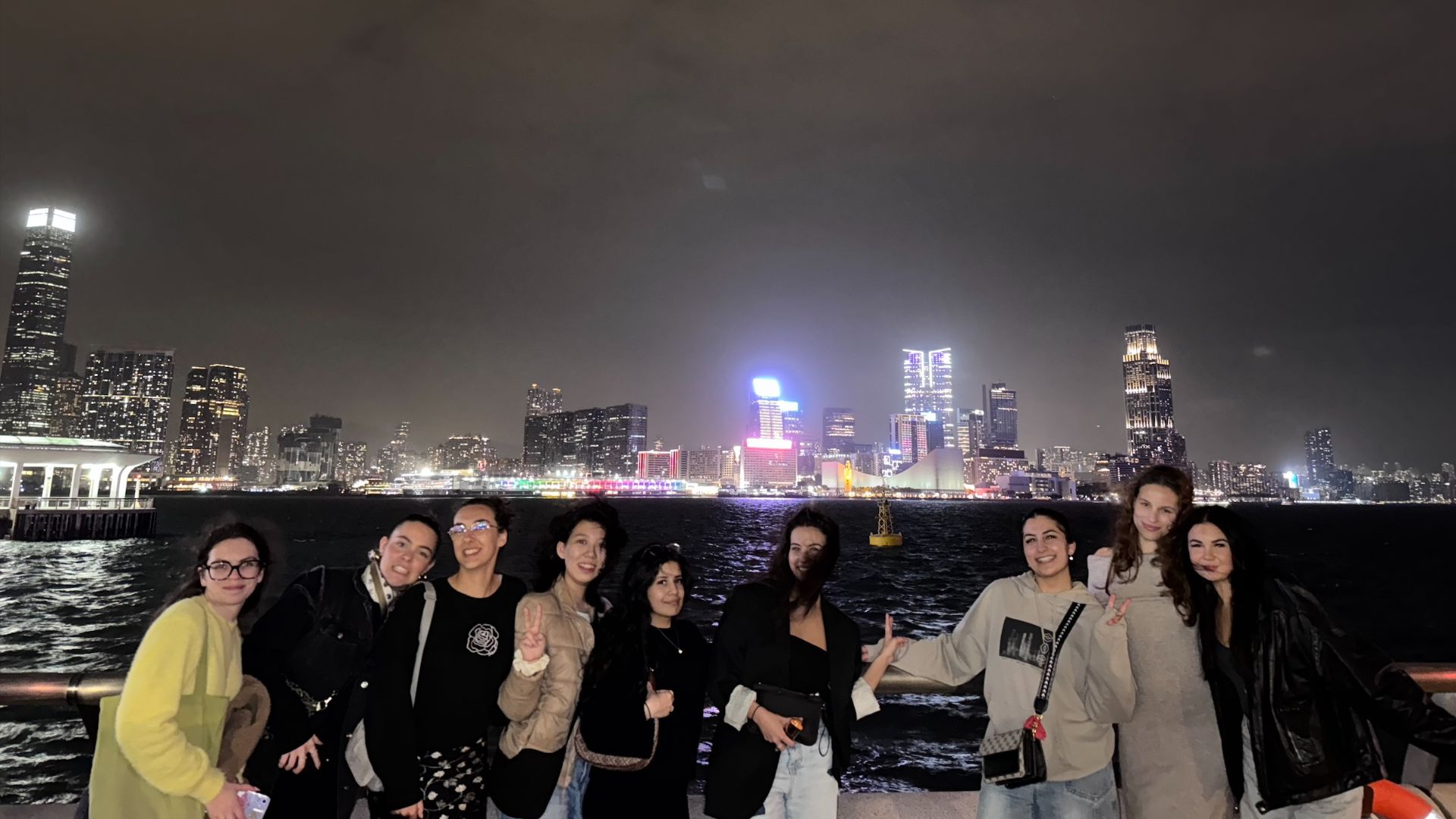 A group of smiling students outside at night in front of a city skyline