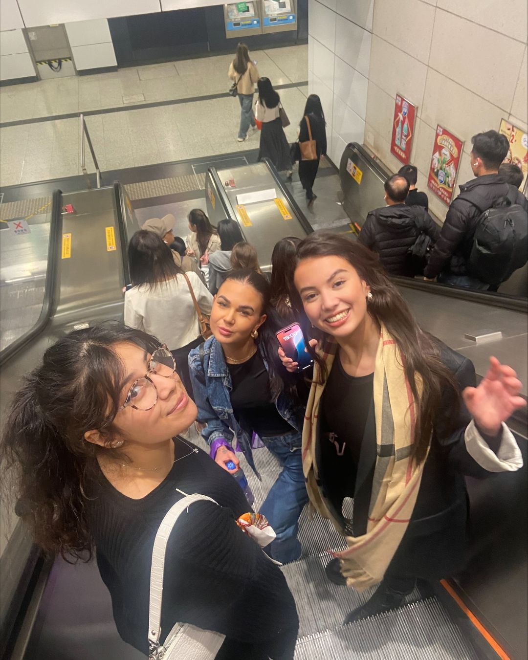 Three students smiling up at the camera on an elevator