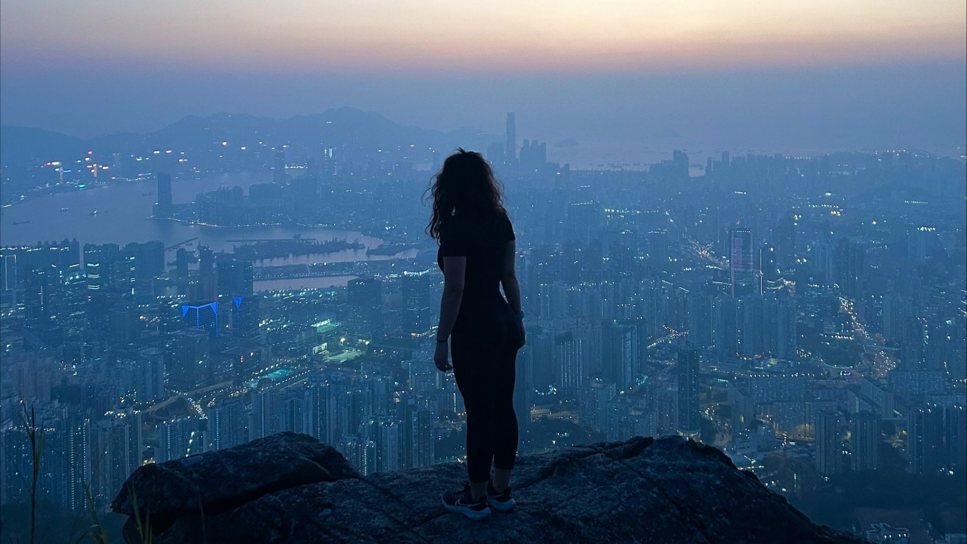 A silhouette of a person over looking a city a sunset
