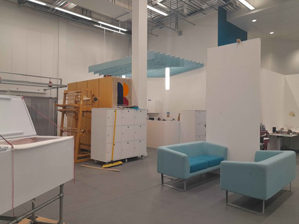 Modern interior of the Barbara Hepwroth building with minimalist furniture, including two turquoise sofas and white storage cabinets.