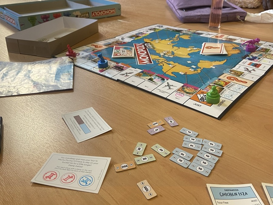 A world monopoly board and pieces spread across a wooden table