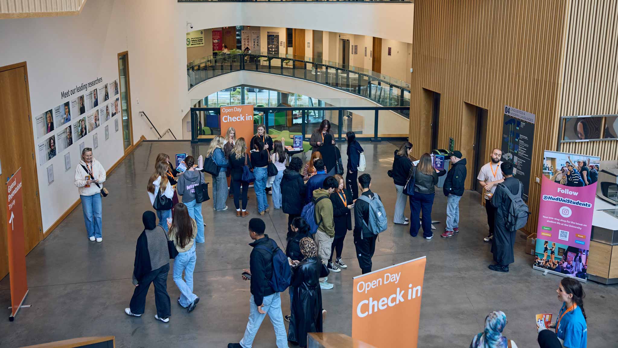 A buy foyer area full of people. Large orange banners say 'Open Day check-in'