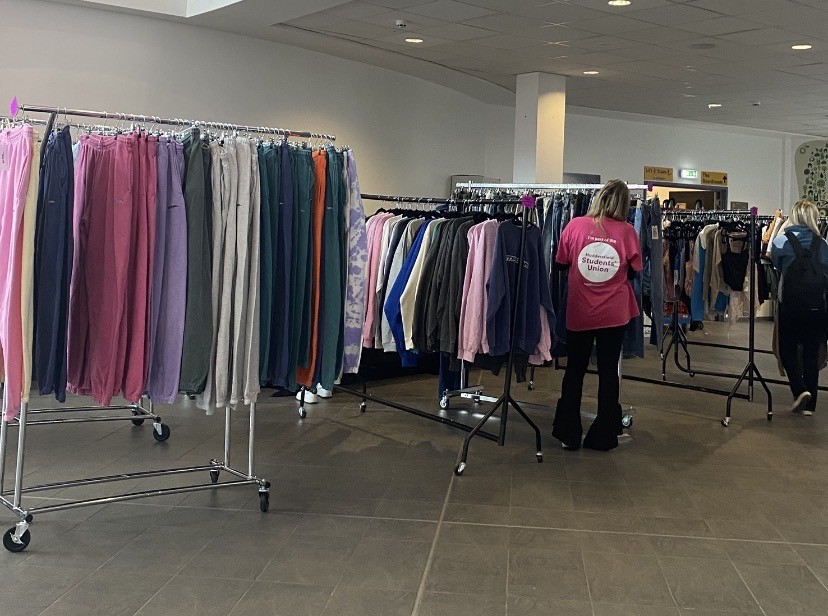 Several rails packed with clothing as part of a pop up university fashion stall