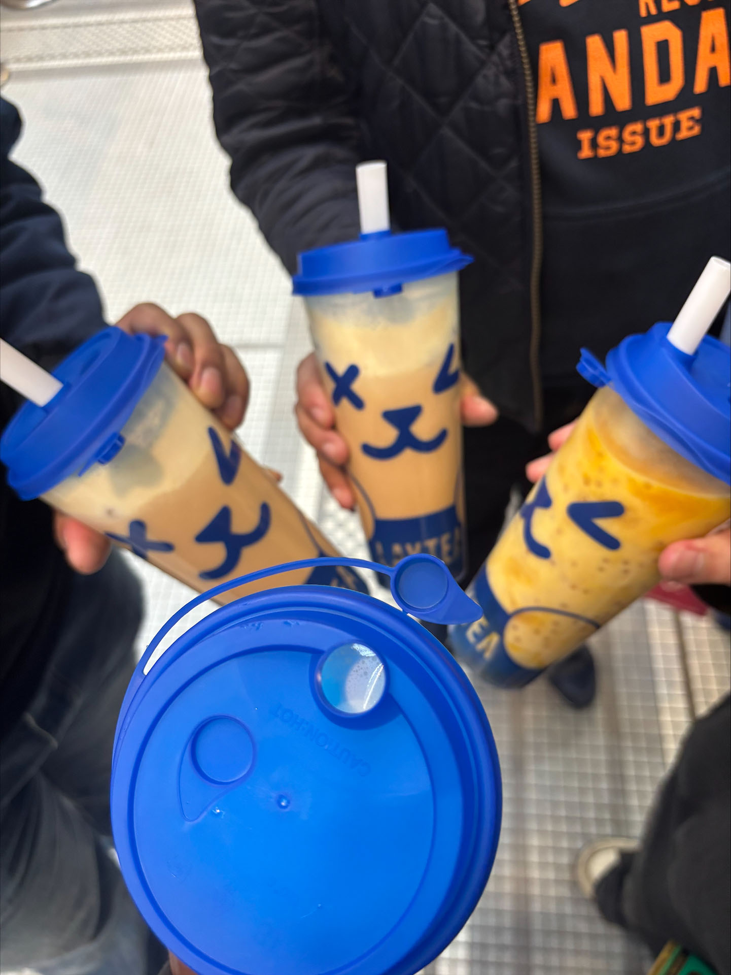 Four people taking a picture of their bubble tea held in a circle.