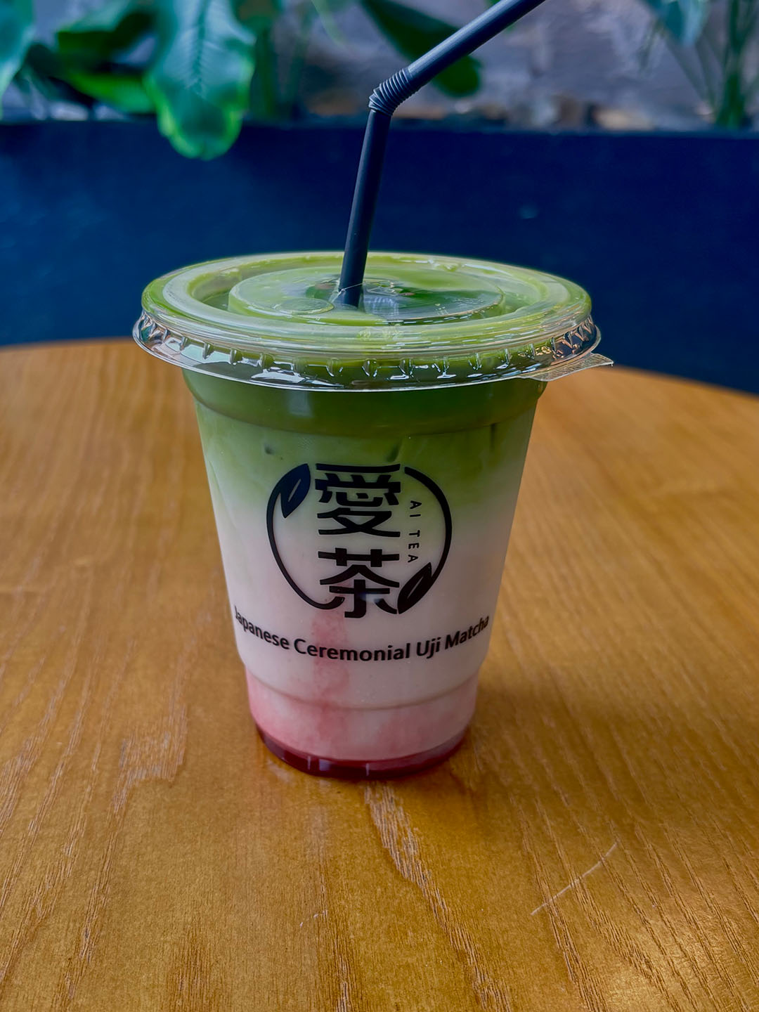 A cup of layered matcha beverage with a visible logo for 