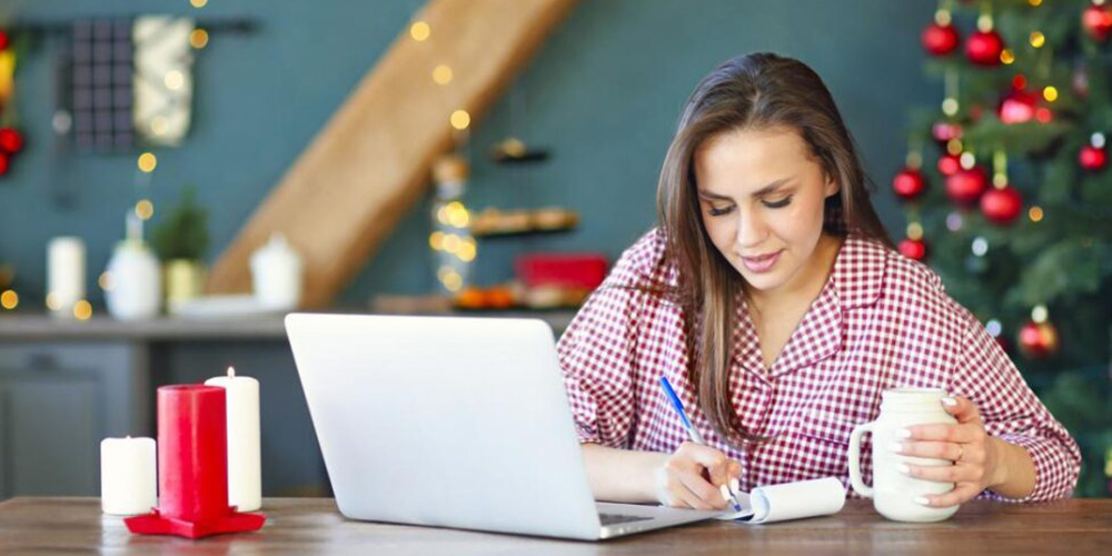 A woman sat at a laptop making notes
