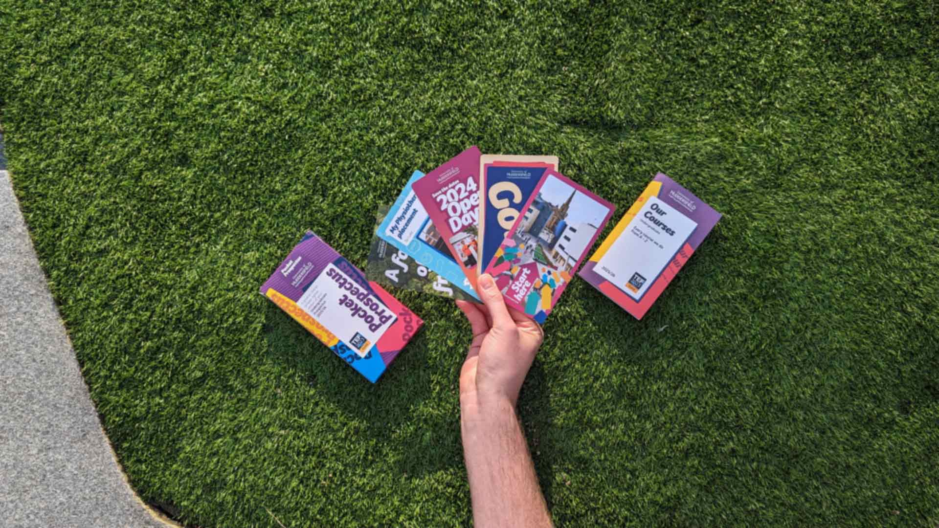 Picture of a hand holding the prospectus on a grassy background