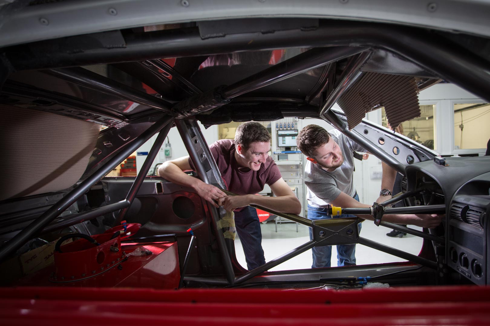 Mechanical Engineering students working on the shell of a car in a Mechanical Laboratory