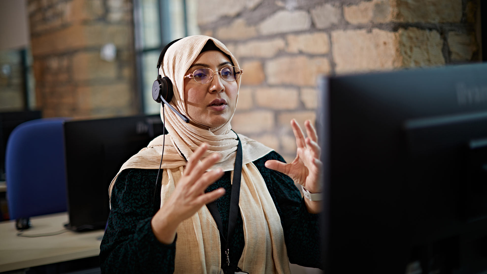 An academic sat at a computer, teaching an online class.