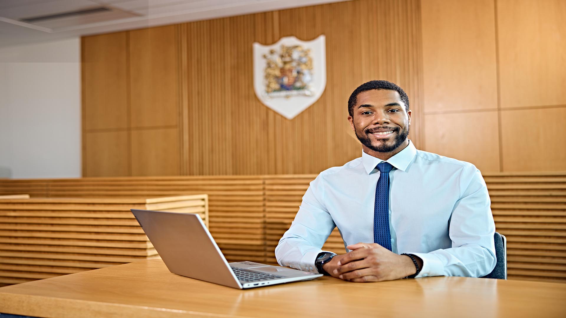 A man smiling in a court room with a laptop