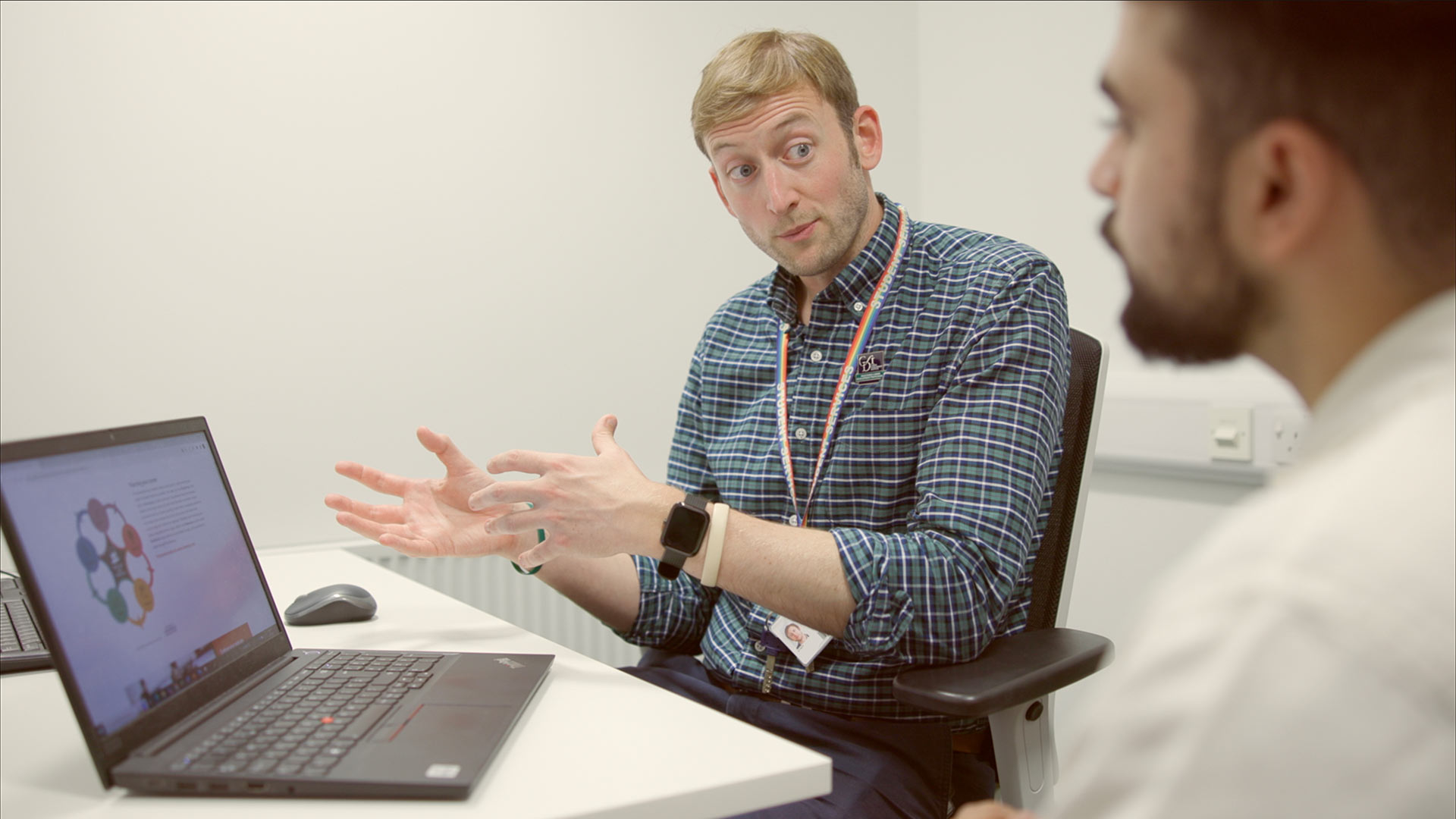 A Career Development professional sat at a desk with a client, with a laptop in-between them.