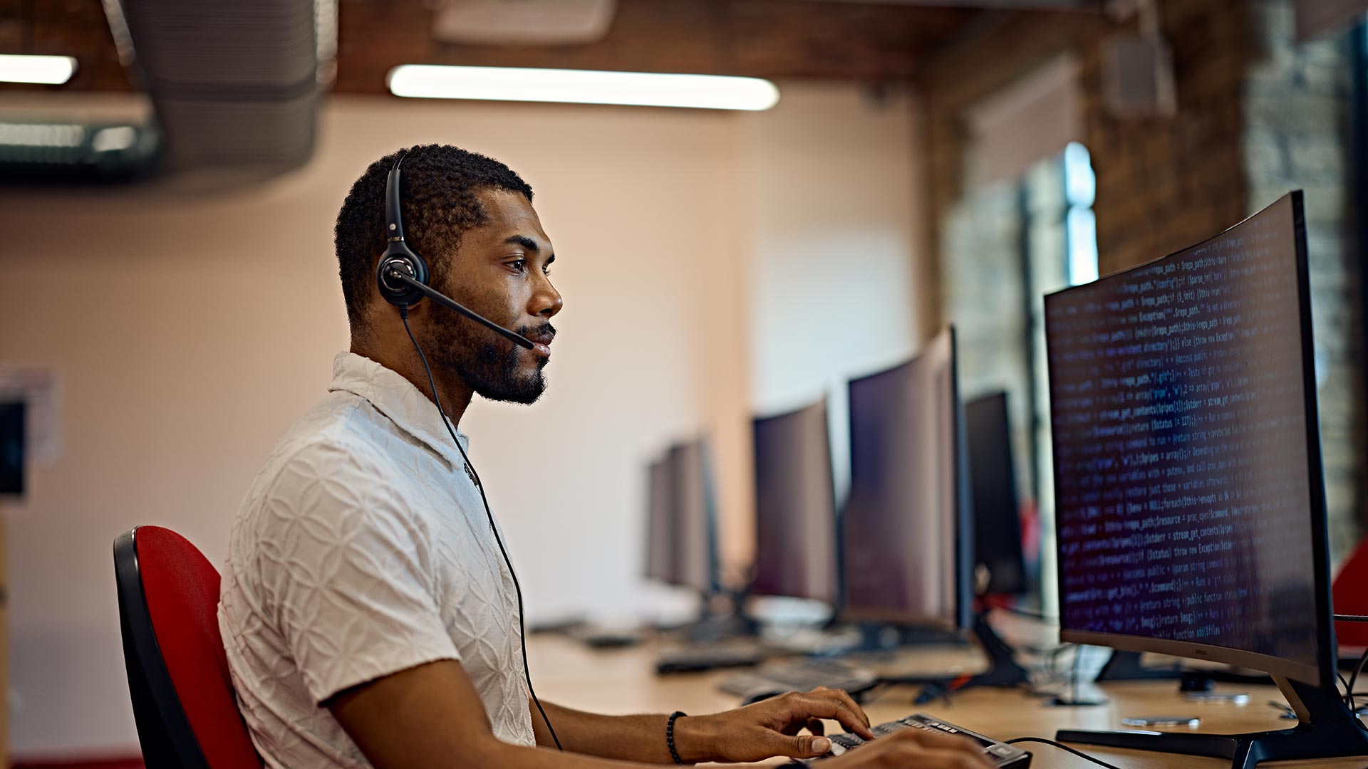 A person wearing a headset, working at a computer.