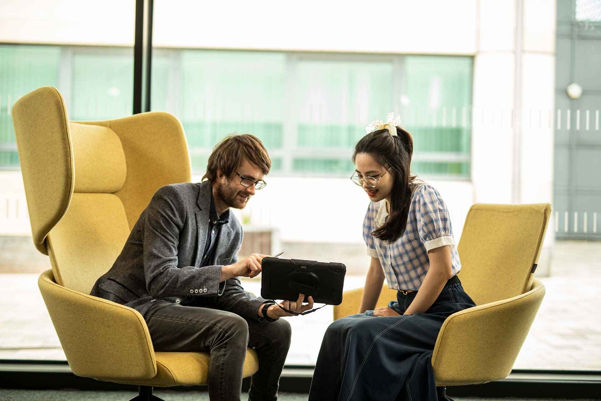 A member of staff showing content on a tablet to a client/student.