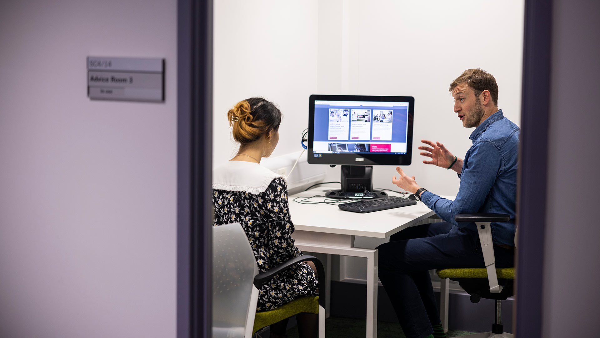 A Career Development professional having a meeting with a client in their office. They are both looking at a computer screen.