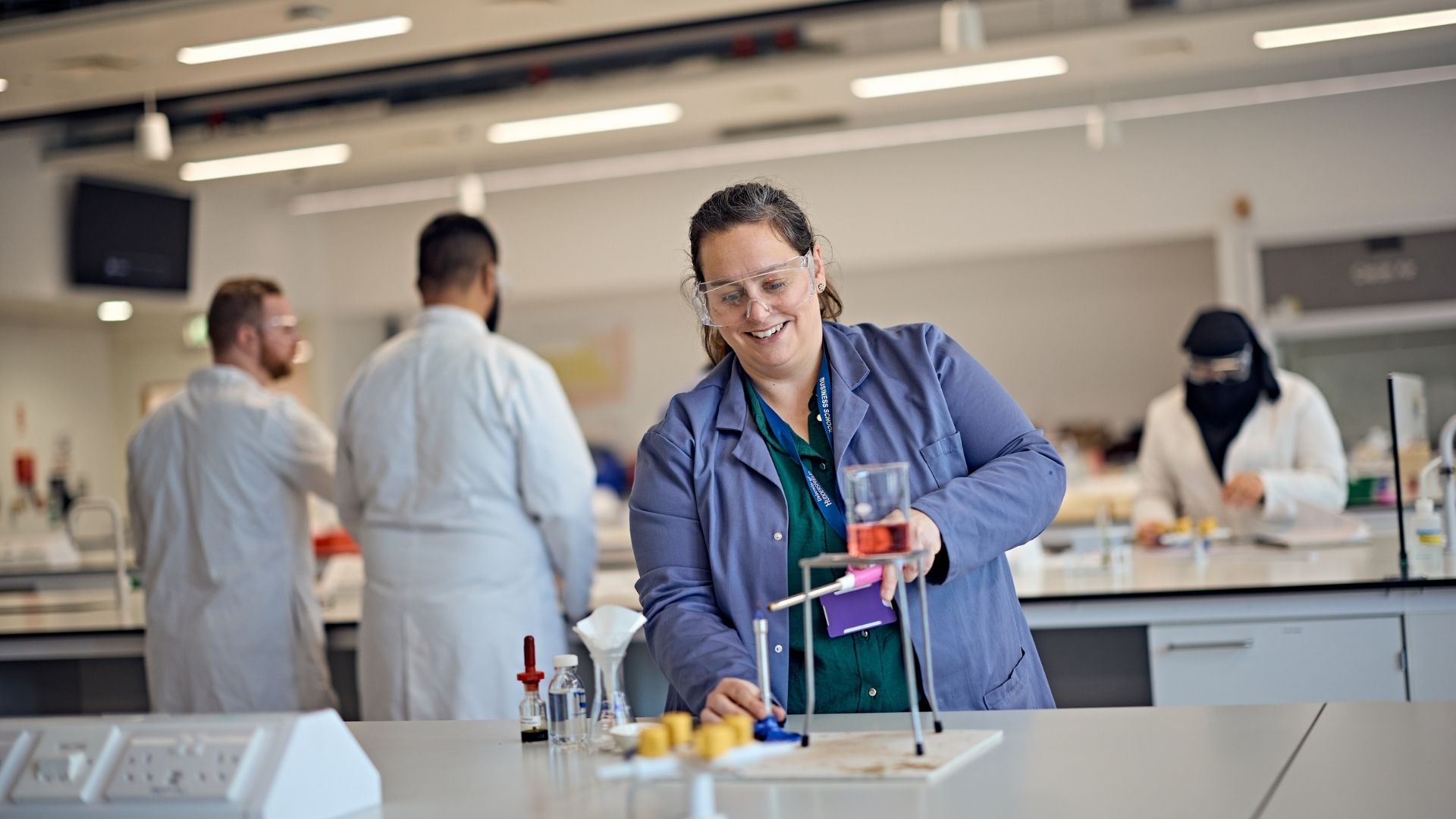 Lecturer with goggles on in science lab doing an experiment