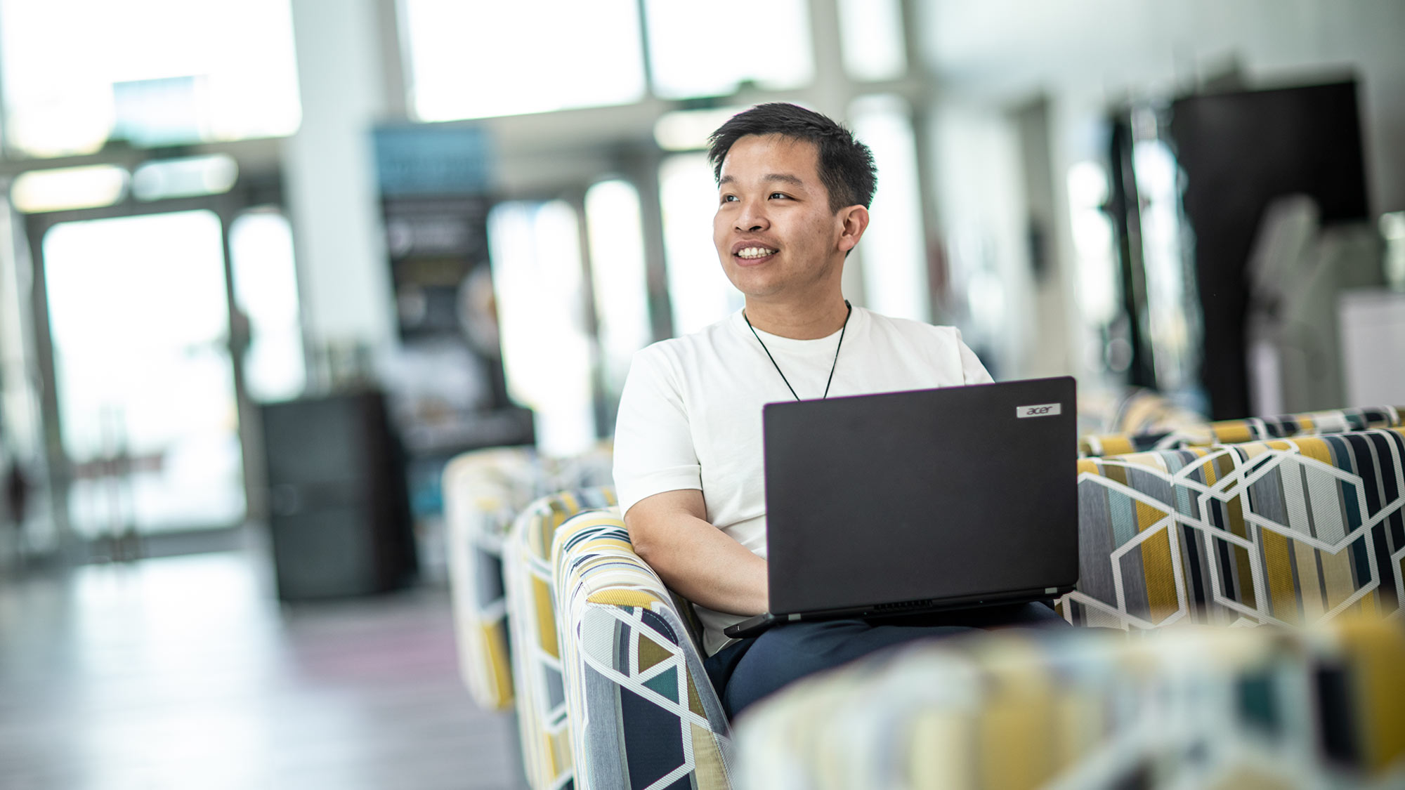 Khoa sits in the Barbara Hepworth Building on his laptop. 